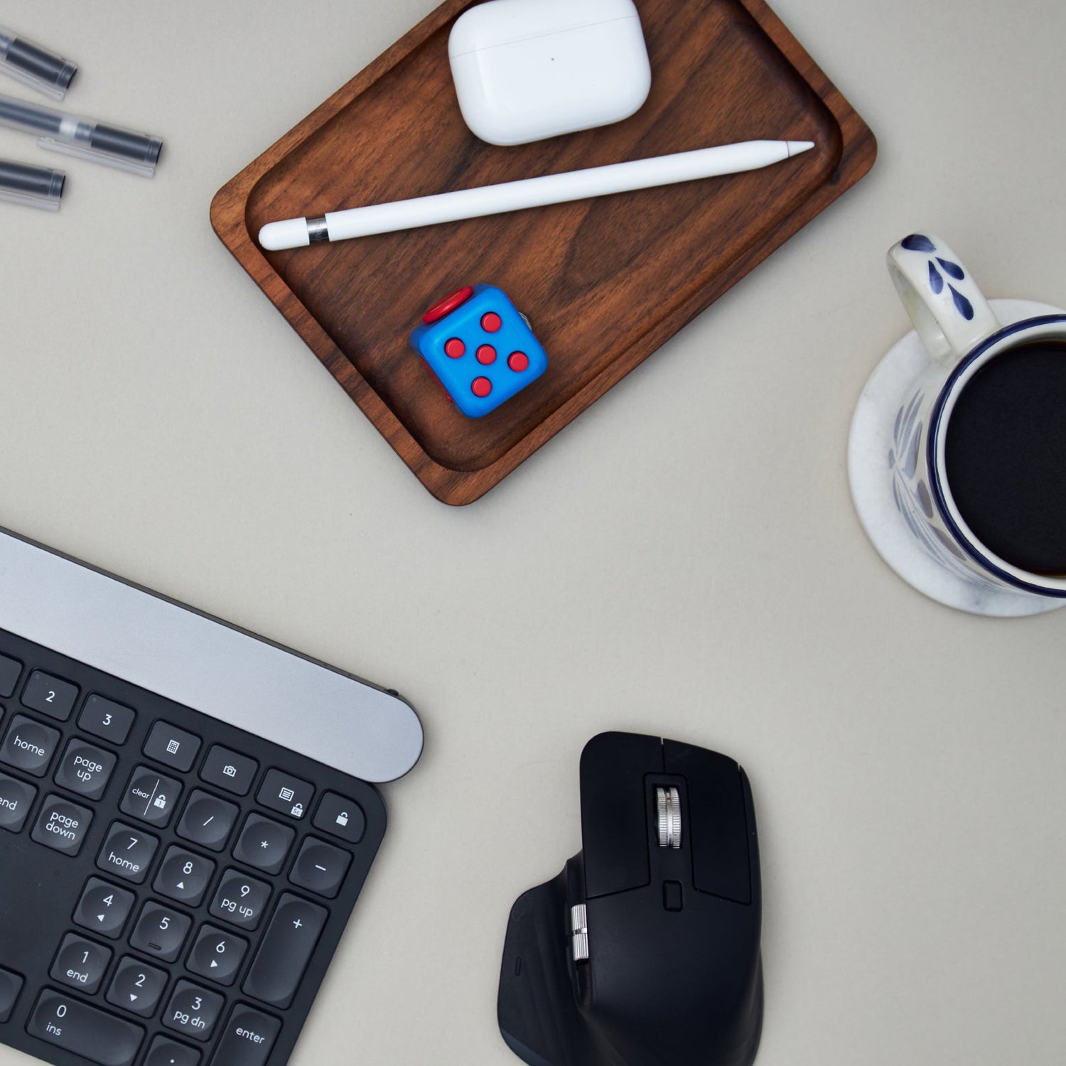 Keyboard, mouse, coffee, and a tray with headphones, a pen, and a die