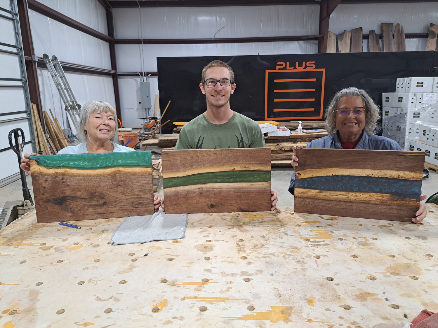 Man and two women smiling, each holding an epoxy river serving tray.